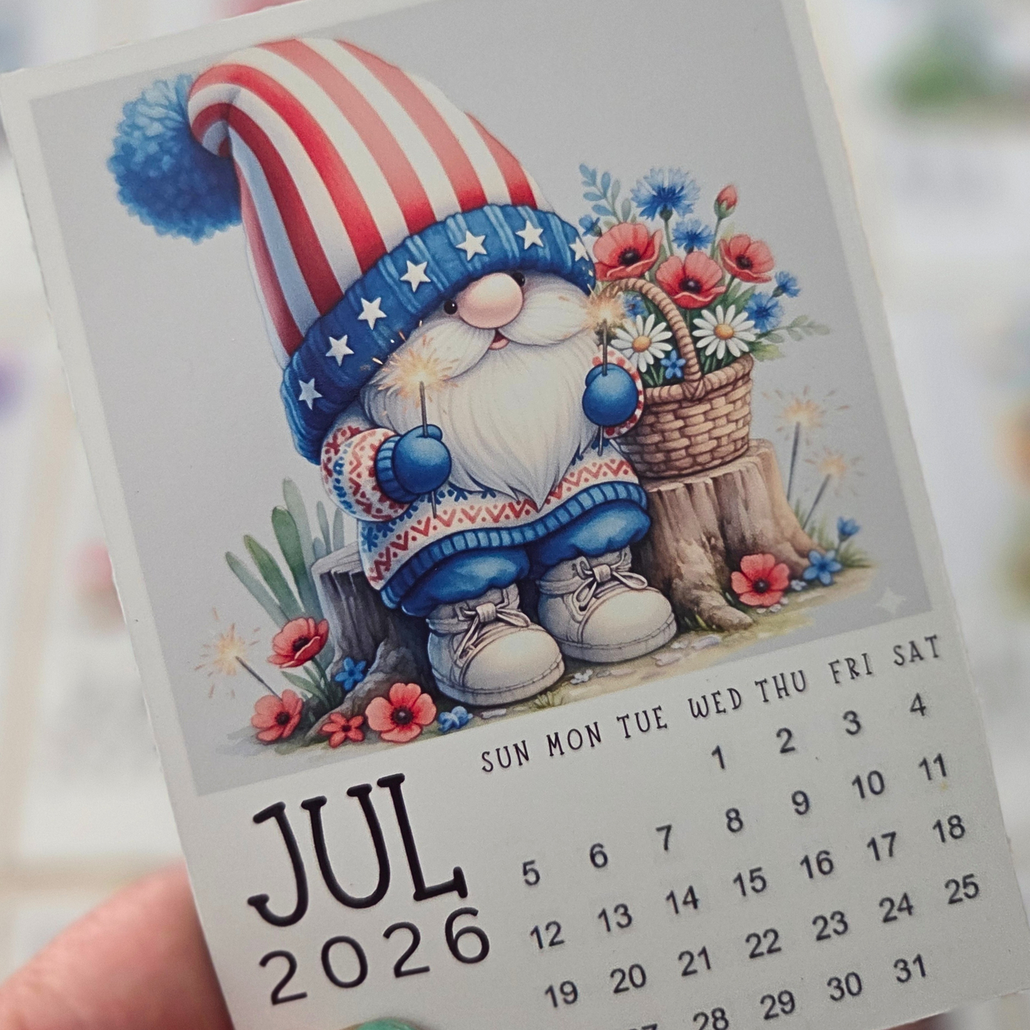 Calendar for July 2026 featuring a gnome with an American flag hat and flowers.