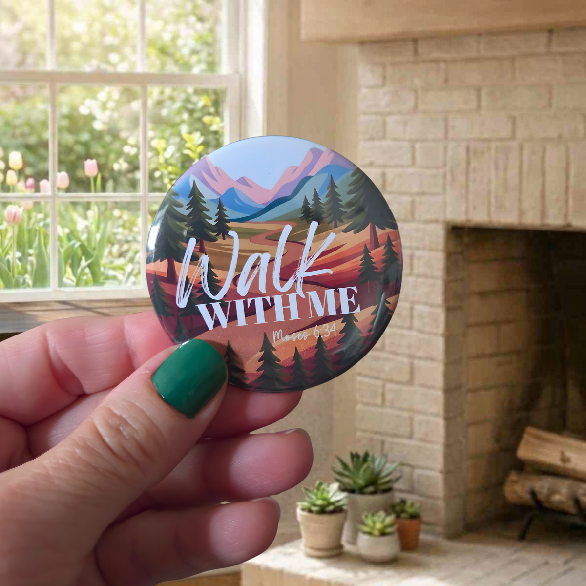 Round ‘Walk With Me’ pin featuring two hikers walking under a crescent moon and stars, surrounded by pine trees and hills, with the scripture reference Moses 6:34.