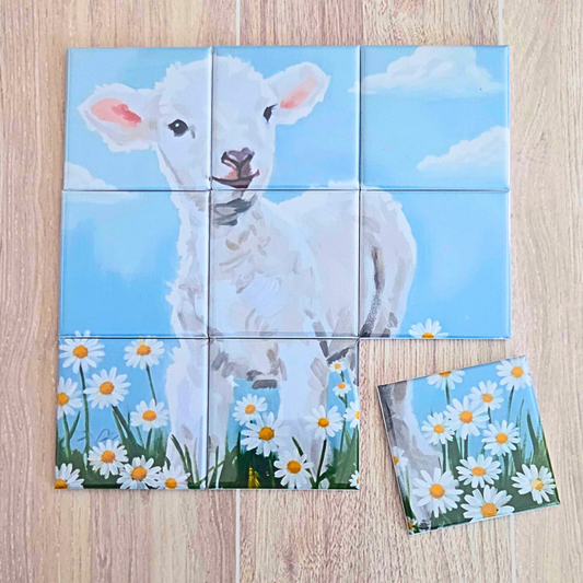 9‑piece magnetic Easter puzzle featuring a painted white lamb standing in a daisy field under a blue sky, with one piece removed to show the puzzle format. Includes a floral drawstring gift bag and a brown tag that reads ‘It’s Not About the Bunny, It’s About the Lamb – Happy Easter.’ Faith‑based Easter gift, Christian lamb puzzle for kids and families.