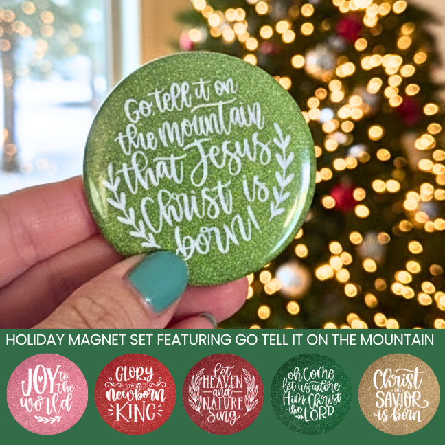 Green holiday magnet with Christmas lyrics held by a hand in front of a blurred Christmas tree.