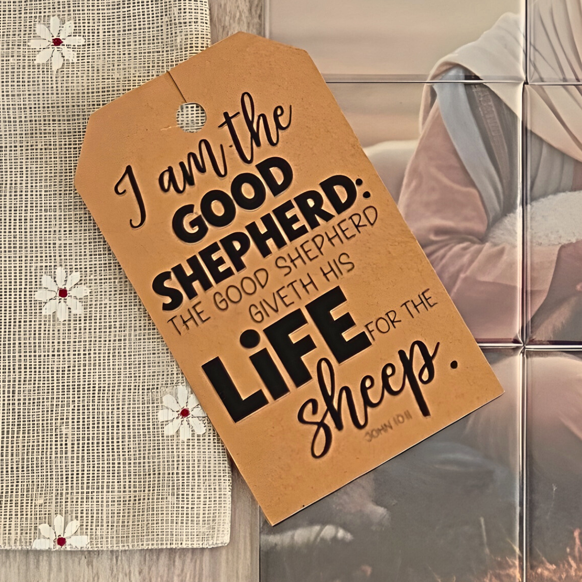 Magnet Puzzle of a Jesus Christ holding a lamb with sheep in the background on a wooden surface. It the Lamb of God puzzle for the Easter season.  show a tag that quotes the Scripture John 10:1 I am the Good Shepherd. The Good Shepherd giveth his life for the sheep.