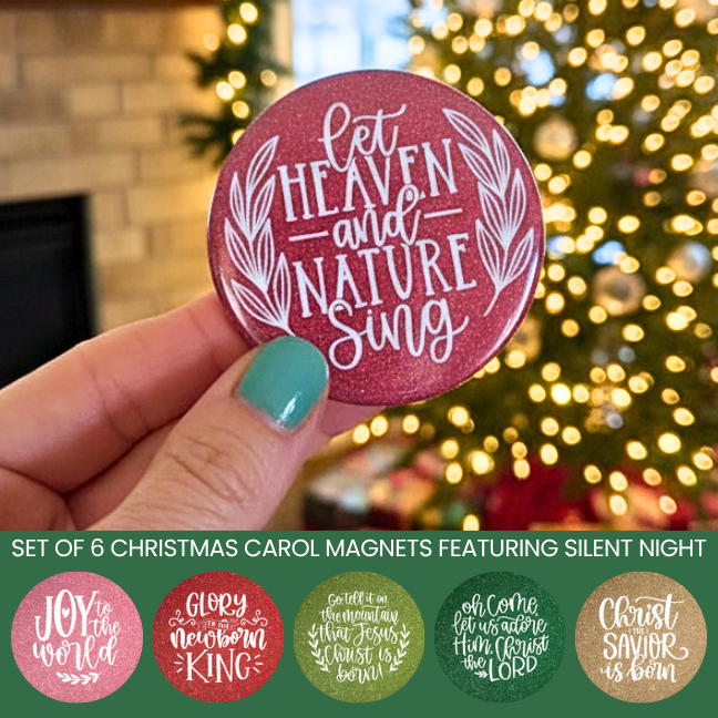 Hand holding a Christmas-themed magnet with 'Let Heaven and Nature Sing' text, blurred Christmas tree in the background.