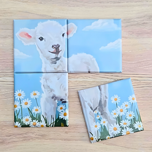 4‑piece mini magnetic Easter puzzle featuring a painted white lamb standing in a field of daisies under a bright blue sky. One small puzzle piece is shown separated to highlight the simple, toddler‑friendly design.