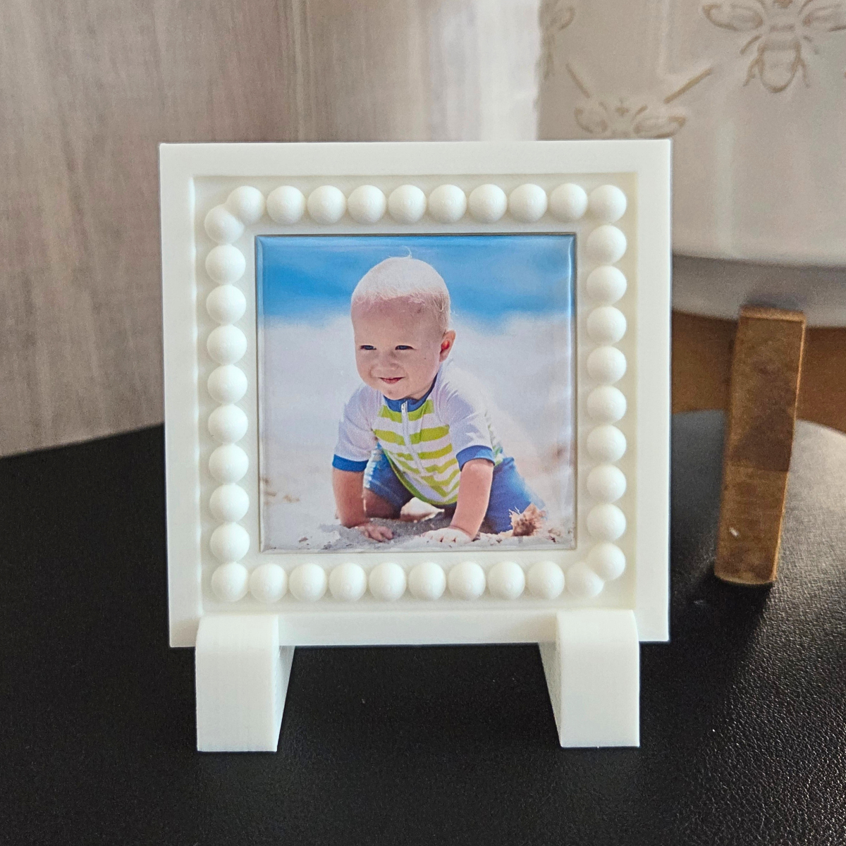 Close‑up of a white 3D‑printed square magnet frame with a beaded border and smooth, modern finish.