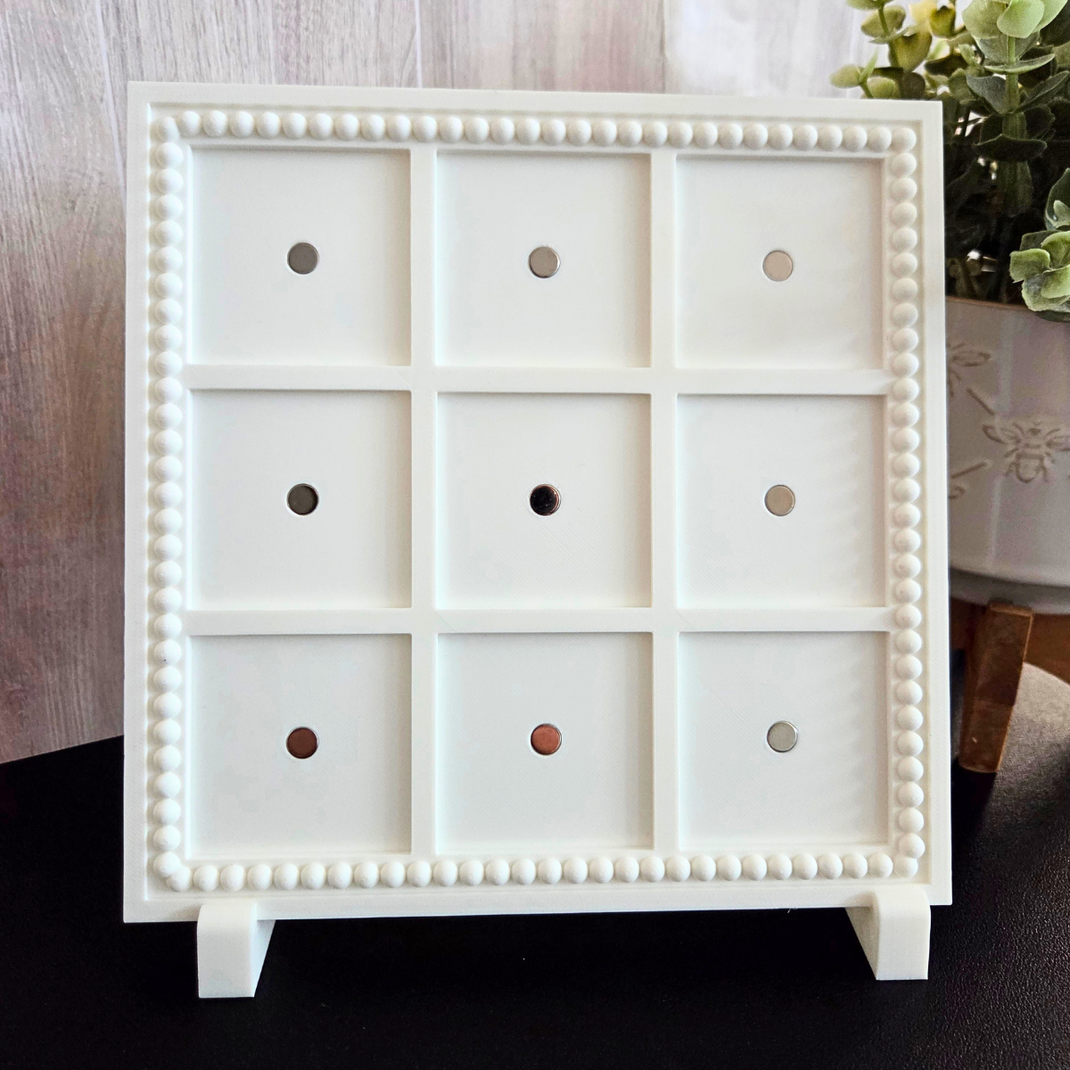 White 3D‑printed 3×3 magnetic frame with a decorative beaded border, designed to hold nine photo magnets in a clean grid layout, shown with removable feet.