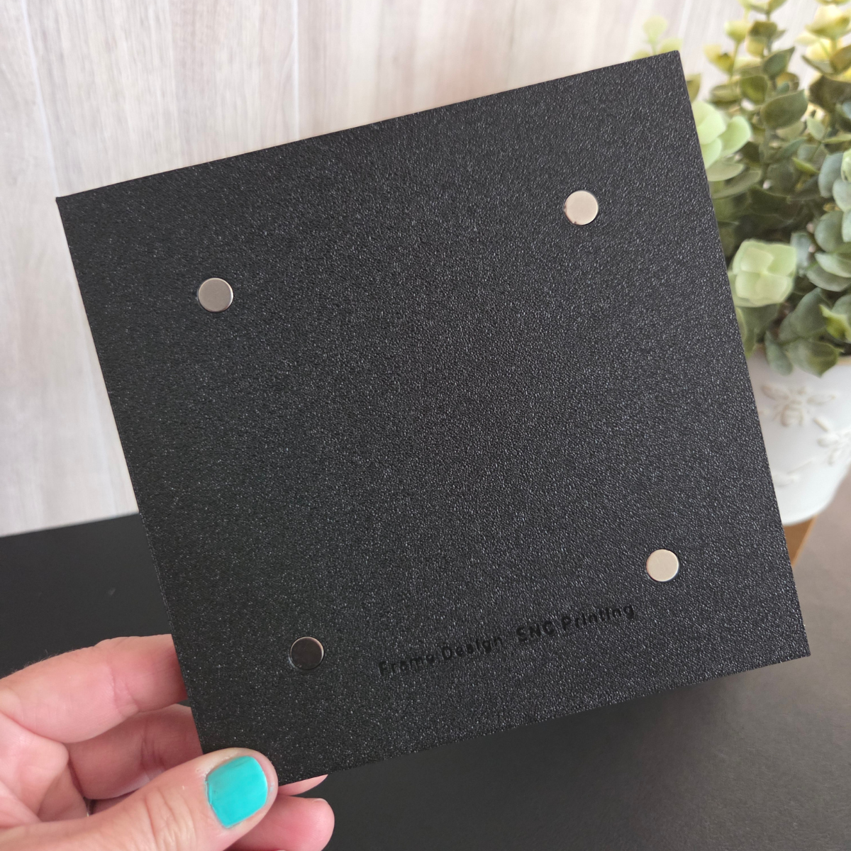 Black 3D‑printed 2x2 magnetic frame with a decorative beaded border, designed to hold 4 photo magnets in portrait or landscape orientation, shown with removable feet.