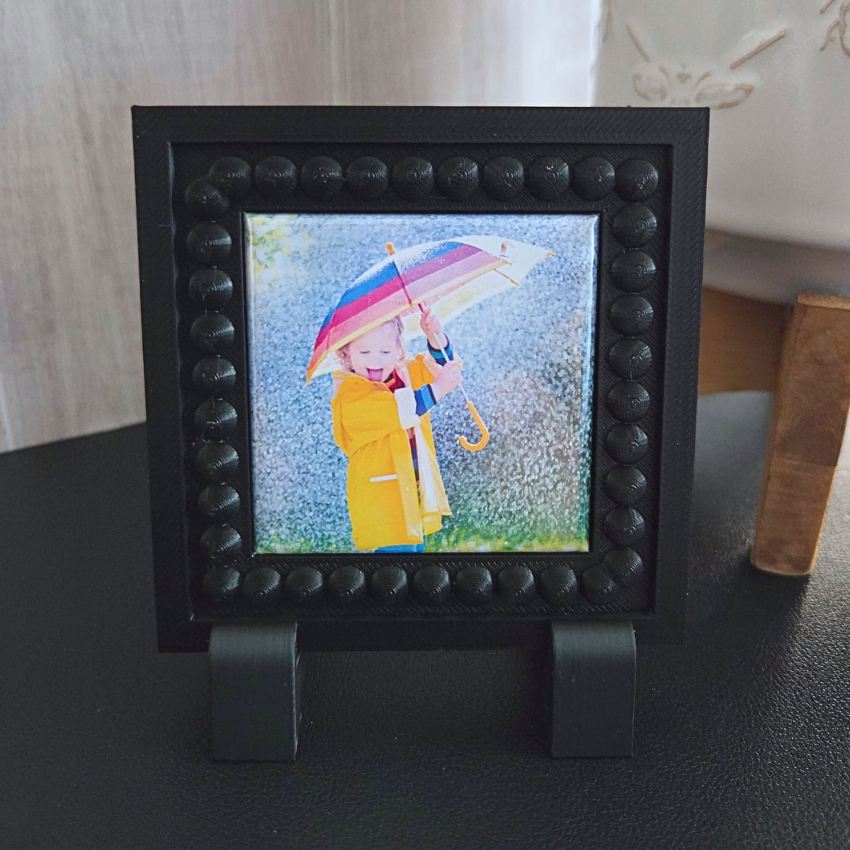 Black single‑magnet frame with built‑in front magnets and a beaded border, displayed on a tabletop.