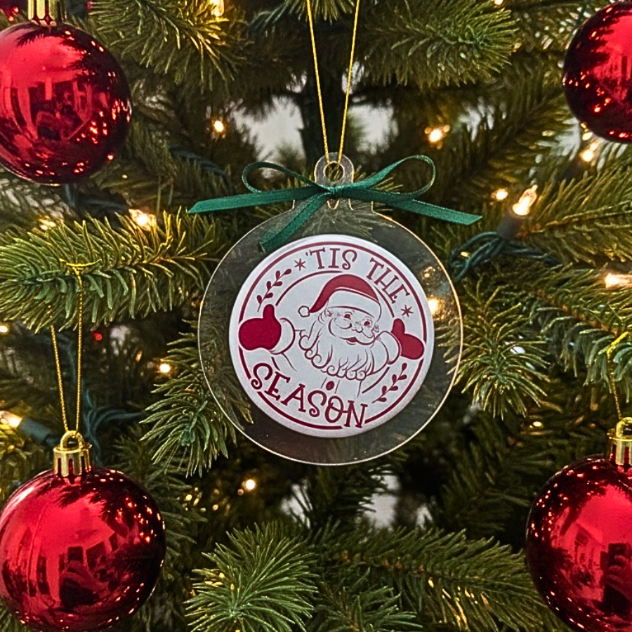 Decorative ornament with 'Tis the Season' text on a Christmas tree with red ornaments.