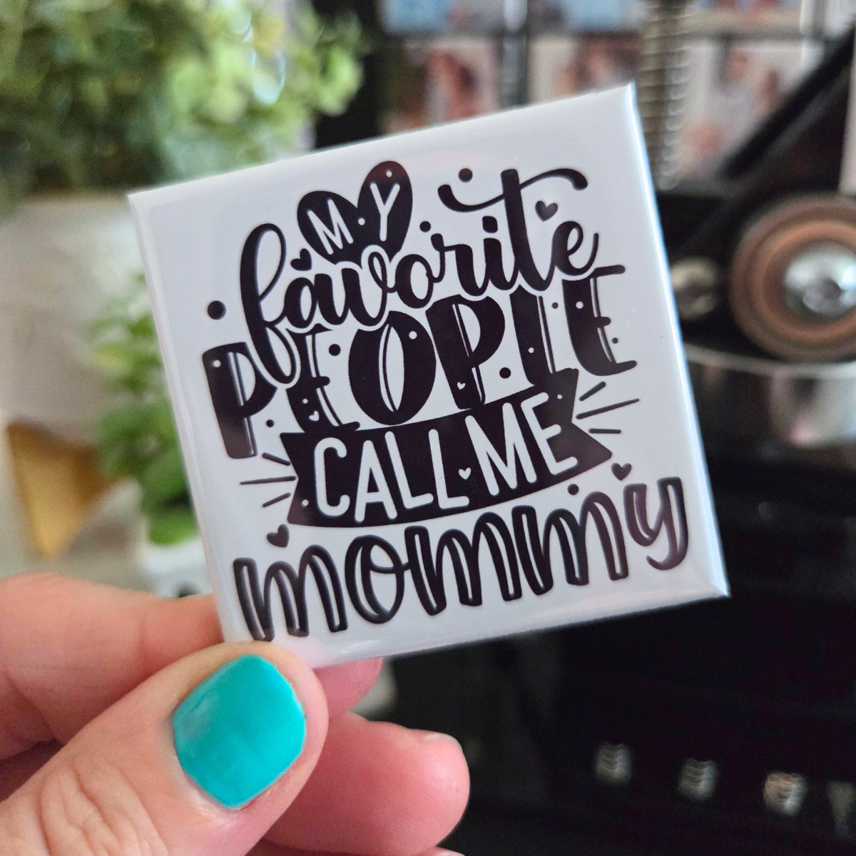 Square magnet with 'My favorite people call me mommy' text held by a hand with teal nail polish.